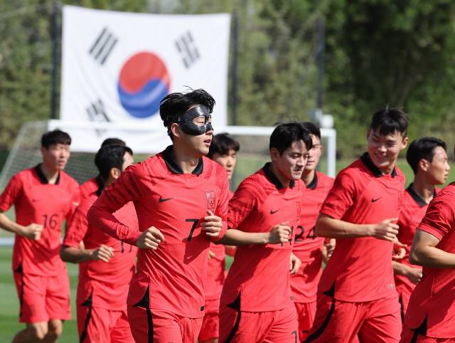 ▲ 안면보호대를 착용한 ‘캡틴’ 손흥민(왼쪽 두번째) 등 축구 국가대표팀 선수들이 16일 오전(현지시간) 카타르 도하의 알에글라 훈련장에서 진행된 첫 ‘완전체’ 훈련에서 러닝을 하며 몸을 풀고 있다. 연합뉴스