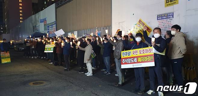 한국주식투자자연합회가 지난 13일 서울 여의도 민주당사 앞에서 금융투자소득세 도입에 반대하는 촛불시위를 하고 있다(한투연 제공).