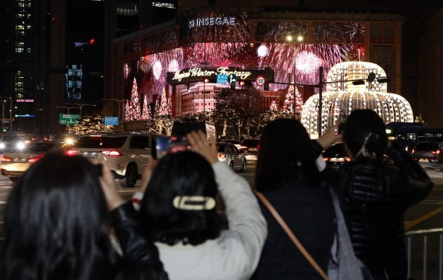 20일 오후 크리스마스 조명으로 화려하게 외벽을 꾸민 서울 중구 신세계백화점 본점 앞 소비자들이 사진을 찍는 모습. 사진=뉴스1