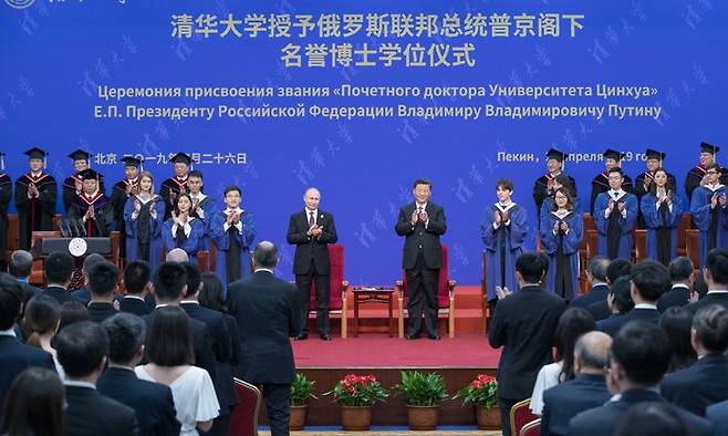 블라드미르 푸틴 대통령이 2019년 4월 중국 베이징 칭화대에서 열린 명예박사학위 수여식에서 시진핑과 나란히 서서 박수치고 있다.