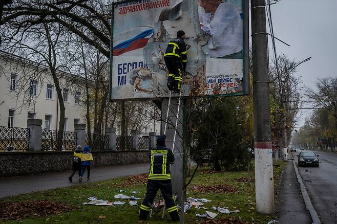 17일(현지시간) 우크라이나 남부 헤르손에서 소방대원들이 러시아의 선전 홍보물을 제거하고 있다. /헤르손 AP=연합뉴스