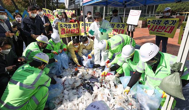 박강수 마포구청장과 구 관계자들이 지난달 11일 오후 서울 마포구청 광장에서 종량제봉투 속에 재활용이 가능한 쓰레기가 얼마나 있는지 확인하기 위해 생활쓰레기 내용물을 확인하고 있다. 연합뉴스