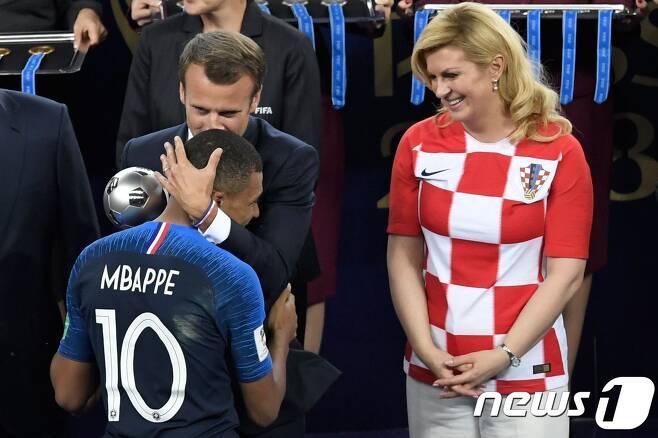 에마뉘엘 마크롱 프랑스 대통령이 모스크바 루즈니키 스타디움에서 열린 프랑스와 크로아티아의 2018 러시아 월드컵 결승전이 끝난 뒤 콜린다 그라바르 키타로비치 크로아티아 대통령이 지켜보는 동안 영플레이어상을 받은 프랑스 대표팀의 킬리안 음바페 끌어안고 축하하고 있다. ⓒ AFP=뉴스1 ⓒ News1 우동명 기자