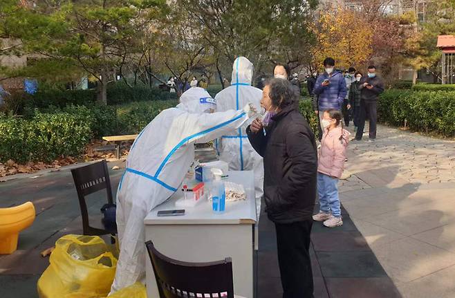 23일 중국 베이징의 봉쇄된 아파트에서 경비원이 주민을 대상으로 PCR 검사를 하고 있다. 연합뉴스