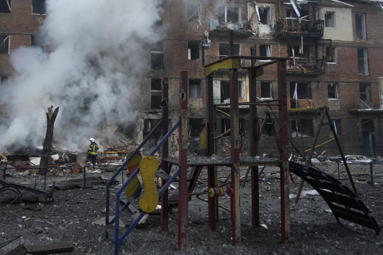 23일(현지시간) 우크라이나 수도 키이우의 한 외곽지역에서 러시아군의 포격으로 화재가 발생하자 소방대원들이 화재를 진압하고 있다. AP·연합뉴스