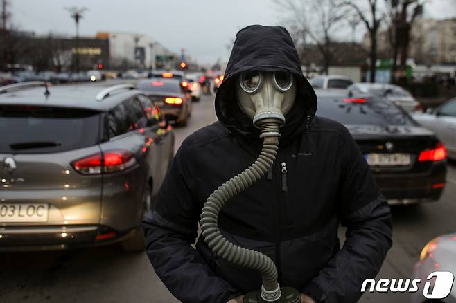 지난 2020년 2월14일(현지시간) 루마니아 부쿠레슈티에서 대기 오염에 항의하는 시위가 벌어졌다. 시위의 일환으로 한 기후 운동가가 차들 사이에서 방독면을 착용하고 있는 모습. 22.02.14 ⓒ 로이터=뉴스1 ⓒ News1 김예슬 기자