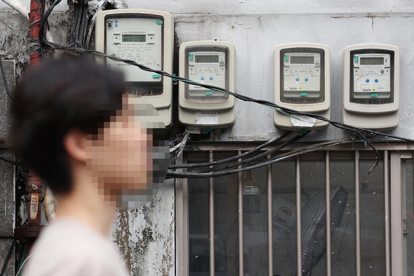한 시민이 전기 계량기 앞을 지나가고 있다. 연합뉴스