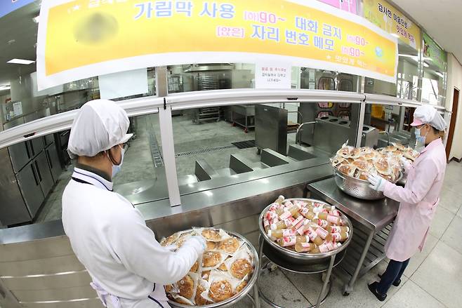 한 고등학교 급식실에서 학교 관계자들이 학생들에게 나눠줄 빵과 음료를 준비하고 있다. [연합]