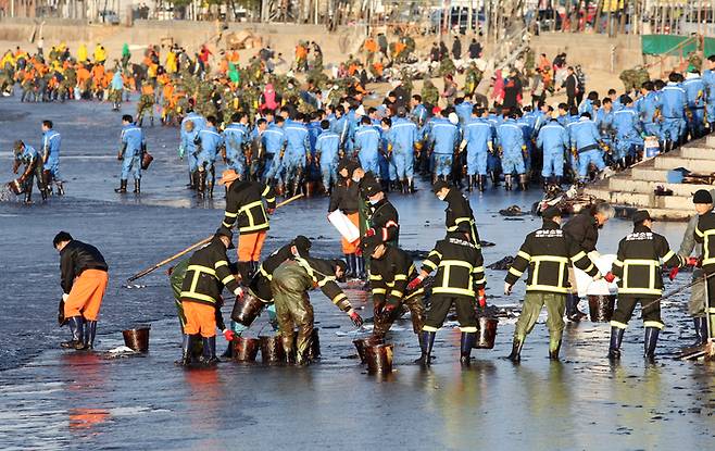 2007년 12월 충남 태안 앞바다에서 기름유출 사고가 발생했을 당시 민관이 힘을 모아 해변으로 몰려든 기름을 제거하는 작업을 하고 있다.  충청남도 제공