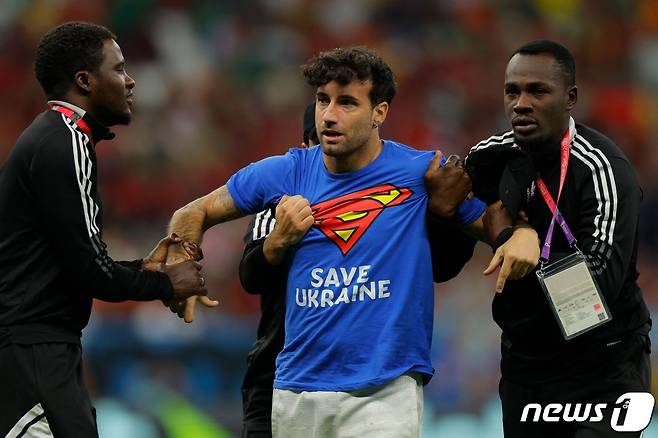 29일(한국시간) 열린 2022 카타르 월드컵 포르투갈-우루과이전 경기 도중 그라운드에 난입한 남성이 보안 요원들에 의해 끌려나가고 있다. ⓒ AFP=뉴스1
