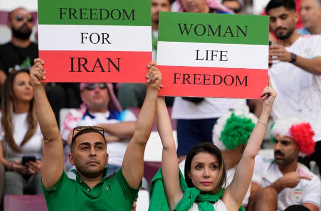 이란 축구팬들이 지난달 21일 카타르 도하 칼리파 국제경기장에서 열린 2022 카타르 월드컵 B조 잉글랜드와의 경기에서 "이란에 자유를" "여성, 생명, 자유"라고 적힌 손팻말을 들고 이란 정부의 탄압을 알리고 있다. 도하=AP 연합뉴스