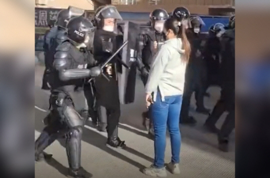 중국 신장에서 발생한 시위 도중 곤봉을 든 경찰을 맨몸으로 막아선 여성. 트위터 영상 캡처