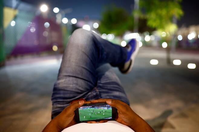 11월 30일 카타르 알라이얀 에듀케이션 시티 스타디움 밖에서 한 축구팬이 프랑스와 튀니지의 경기를 스마트폰으로 보고 있다./로이터 연합뉴스
