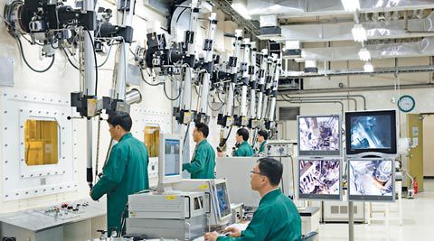 대전 한국원자력연구원에 있는 파이로 프로세싱 연구실에서 연구원들이 로봇팔로 방사능 차폐장치 내부에 있는 폐연료봉을 조작하고 있다.