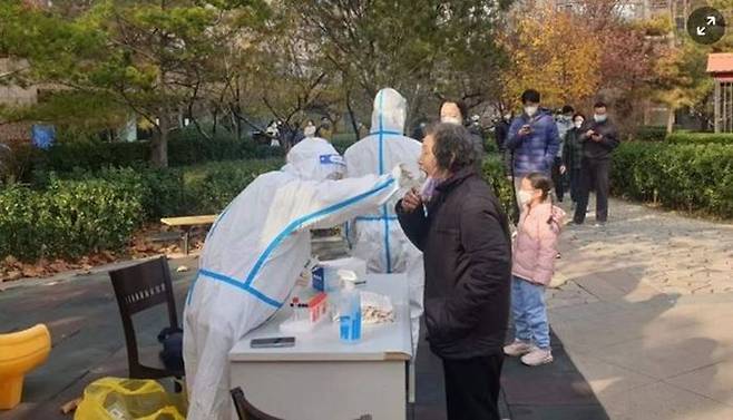 지난달 23일 중국 베이징의 봉쇄된 아파트에서 경비원이 주민을 대상으로 PCR 검사를 하고 있다. ⓒ 연합뉴스
