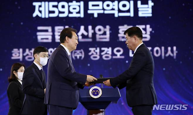 [서울=뉴시스] 전신 기자 = 윤석열 대통령이 5일 서울 삼성동 코엑스에서 열린 제59회 무역의날 기념식에서 희성피엠텍 정경오 대표이사에게 금탑산업훈장을 포상하고 있다. 2022.12.05. photo1006@newsis.com