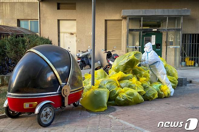 5일 중국 베이징에서 방역복을 입은 요원이 주민들이 격리 중인 건물 밖에 의료폐기물 봉지를 쌓고 있다. 2022.12.05/뉴스1 ⓒ 로이터=뉴스1