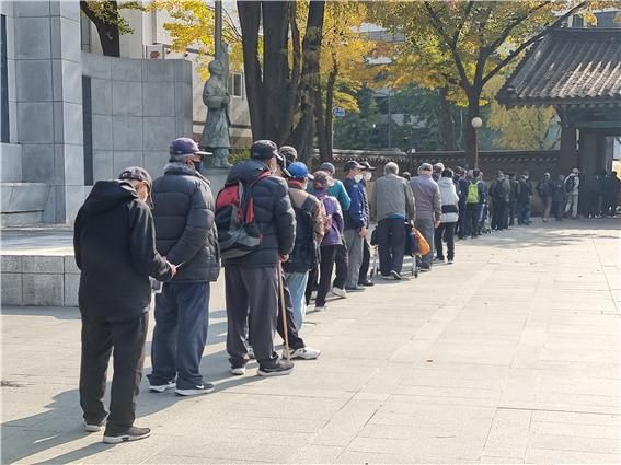 무료 급식을 기다리는 긴 줄이 탑골공원 안까지 기다랗게 늘어져 있다