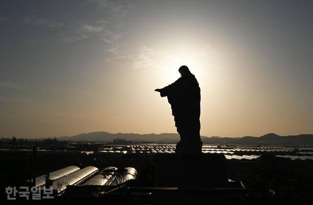 익산 나바위성당의 예수상 아래로 비닐하우스 농지가 펼쳐져 있다. 김대건 신부가 귀국길에 발을 디딘 곳으로, 그 옛날에는 성당 바로 아래까지 금강 물길이 이어졌다고 한다.