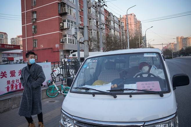 6일(현지시간) 중국 베이징에서 한 시민이 코로나19 예방관리 지원 차량에서 잠든 자원봉사자를 바라보고 있다. 감염자 수 증가에도 베이징과 광저우 같은 도시는 코로나 검사와 격리규제 완화를 위한 조치를 취하고 있다. 경기침체가 우려되는 가운데 중국 정부가 '제로 코로나' 정책을 완화하면서 이날부터 베이징 내 쇼핑몰과 슈퍼마켓 출입을 위한 코로나19 음성 확인서 제출이 필요 없게 됐다. [연합]