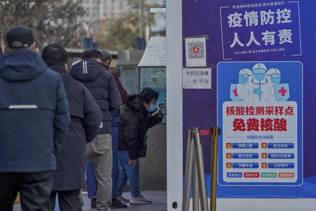 베이징 시민들이 7일 코로나19 유전자증폭(PCR) 검사를 받기 위해 길게 줄 서 있다. 중국 국무원은 지역간 이동이나 시설 출입을 위한 PCR 음성 증명 요구를 대거 폐지하는 내용을 담은 새로운 정책을 발표했다. AP연합.