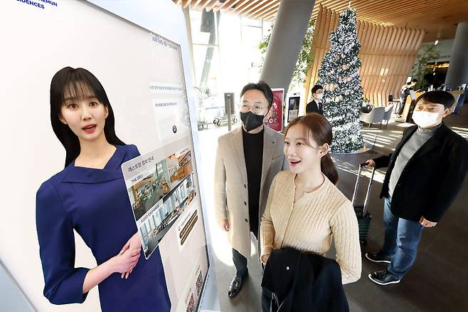 KT 모델이 노보텔 앰배서더 서울 동대문 호텔＆레지던스 1층 로비에 설치된 AI 컨시어지 앞에서 안내를 받고 있다.