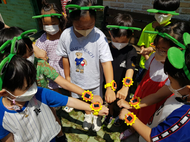 부산 푸른누리 작은도서관을 방문한 어린이들이 남부발전과 한국에너지정보문화재단이 기획한 프로그램에서 태양광 팔찌를 만들어 손목을 내보이고 있다.