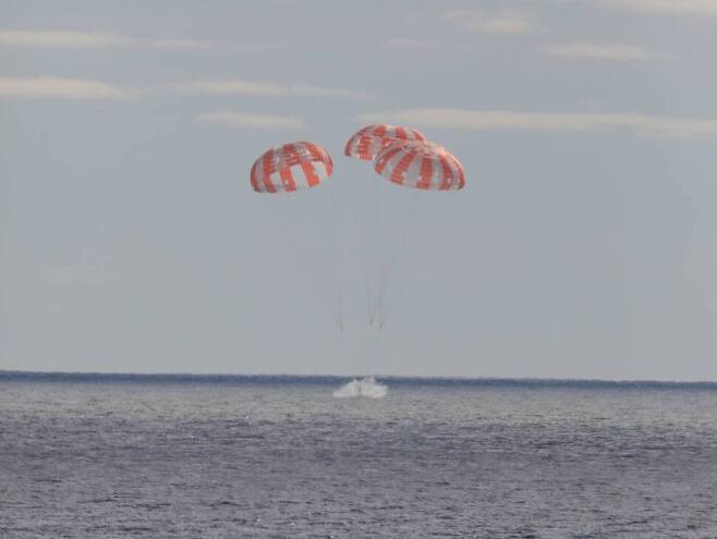 아르테미스 1호 임무의 오리온 우주선이 낙하산을 편 채 11일 오전 9시40분(현지시각) 태평양에 착수하고 있다. 나사 제공