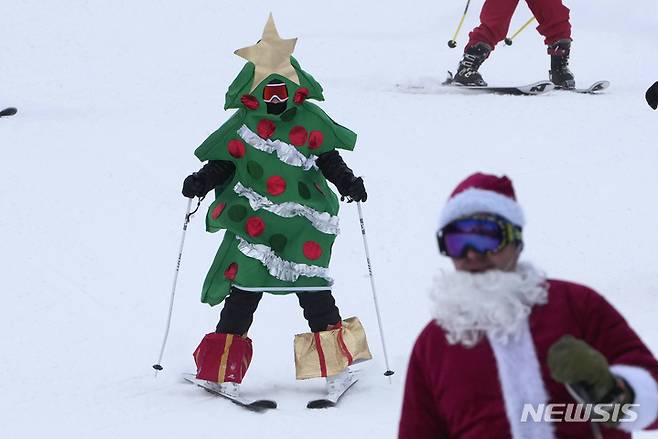 [뉴리=AP/뉴시스] 11일(현지시간) 미국 메인주 뉴리의 선데이 리버 스키 리조트에서 크리스마스 트리 복장을 한 스키어가 스키를 타고 있다. 2022.12.12.