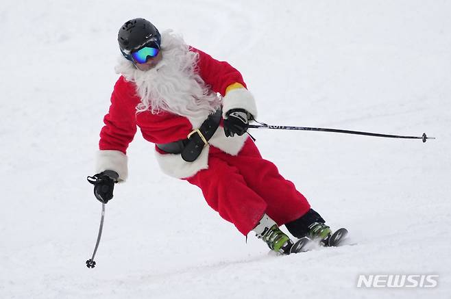 [뉴리=AP/뉴시스] 11일(현지시간) 미국 메인주 뉴리의 선데이 리버 스키 리조트에서 산타클로스 복장을 한 스키어가 스키를 타고 있다. 2022.12.12.
