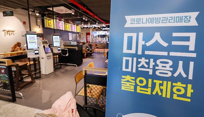 정부가 이달 말까지 실내 마스크 착용 의무를 조정하는 로드맵을 내놓을 예정인 가운데 12월11일 오후 인천국제공항 제2여객터미널의 한 매장에 마스크 착용 안내문이 세워져 있다. ⓒ 연합뉴스