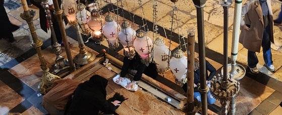 십자가에서 숨진 예수의 주검을 눕혔다고 전해지는 돌이다. 그 돌에 손을 올리고 순례객들이 기도를 하고 있다. 백성호 기자