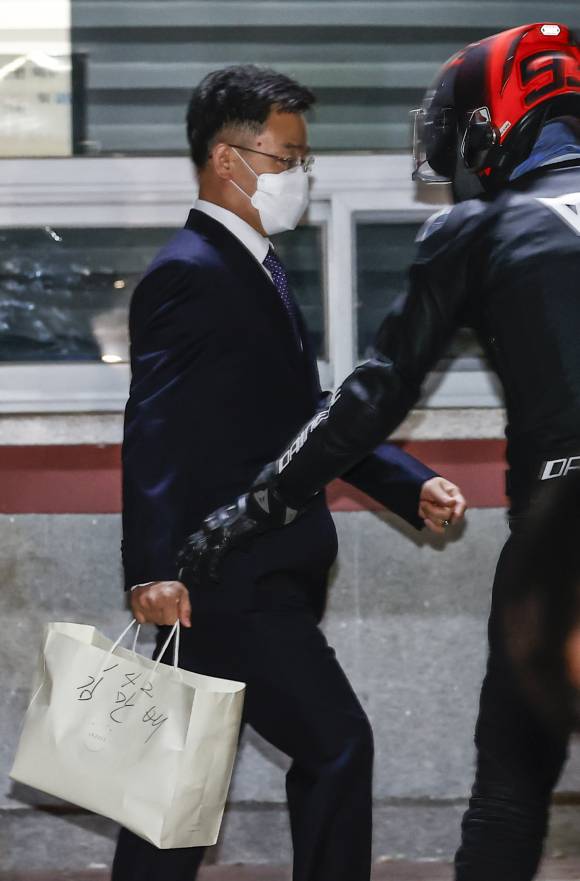 2021년 10월15일 화천대유 대주주 김만배씨가 구속영장 기각으로 경기도 의왕 서울구치소를 나서고 있는 가운데 측근인 최우향씨가 헬멧을 쓰고 나타나 김씨의 짐을 건네 받고 있다. ⓒ 연합뉴스