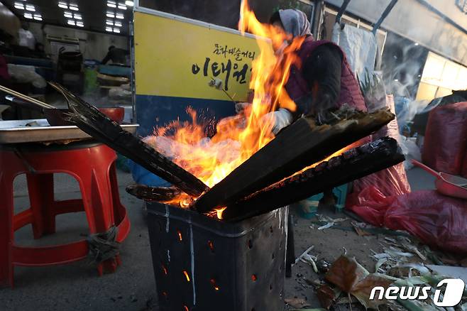 (대구=뉴스1) 남승렬 기자 = 휴일인 18일 이번 겨울 최강 한파에 대구 도심 분위기가 크게 움츠러들었다. 북서쪽에서 찬 공기가 남하하면서 칼바람까지 더해 체감온도는 -10도 아래까지 곤두박질쳤다. 사진은 지난 14일 대구 칠성시장에서 상인이 모닥불을 쬐며 장사 준비를 하는 모습. 2022.12.14/뉴스1 ⓒ News1 공정식 기자