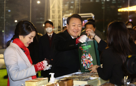 윤석열 대통령과 김건희 여사가 지난 16일 서울 종로구 열린송현광장에서 열린 윈·윈터 페스티벌 개막식에서 에어돔 부스를 방문, 물건을 구입하고 있다. 연합뉴스