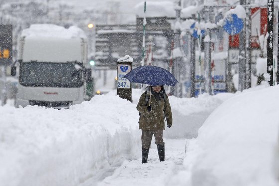 지난 20일 일본 니가타현에서 한 여성이 폭설을 헤치며 걸어가고 있다. AP=연합뉴스