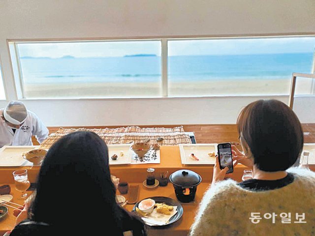 바다 뷰가 좋은 식당에서 요리사가 즉석에서 만든 초밥을 맛보는 관광객들.