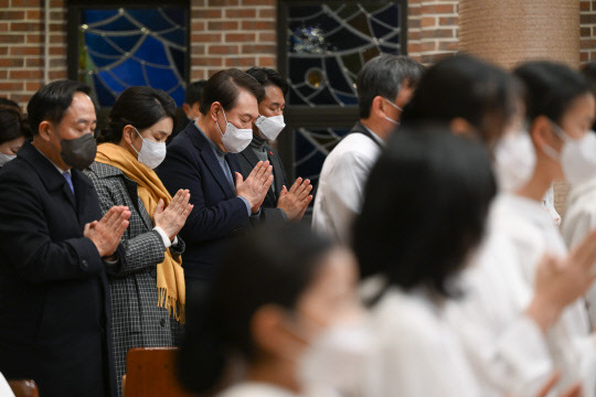 윤석열 대통령과 김건희 여사가 24일 서울 중구 약현성당에서 열린 '주님 성탄 대축일 미사'에 참석해 기도하고 있다.  연합뉴스