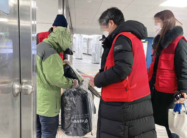 브릿지센터 상담원들이 8일 오후 9시쯤 서울 광화문역 안에서 노숙인에게 침낭을 지급하고 있다. 최은서 기자