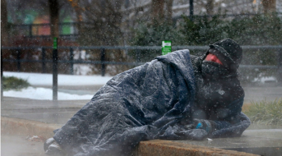 22일(현지시간) 미 미주리주 세인트루이스의 키러 플라자 근처에서 한 노숙인이 맨홀 뚜껑에서 나오는 따뜻한 증기로 몸을 녹이고 있다. [사진=뉴시스]