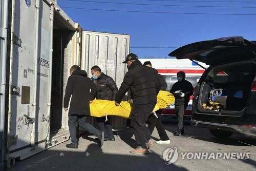 포화 상태 베이징 화장장서 컨테이너로 시신 옮기는 직원들  [AP=연합뉴스]