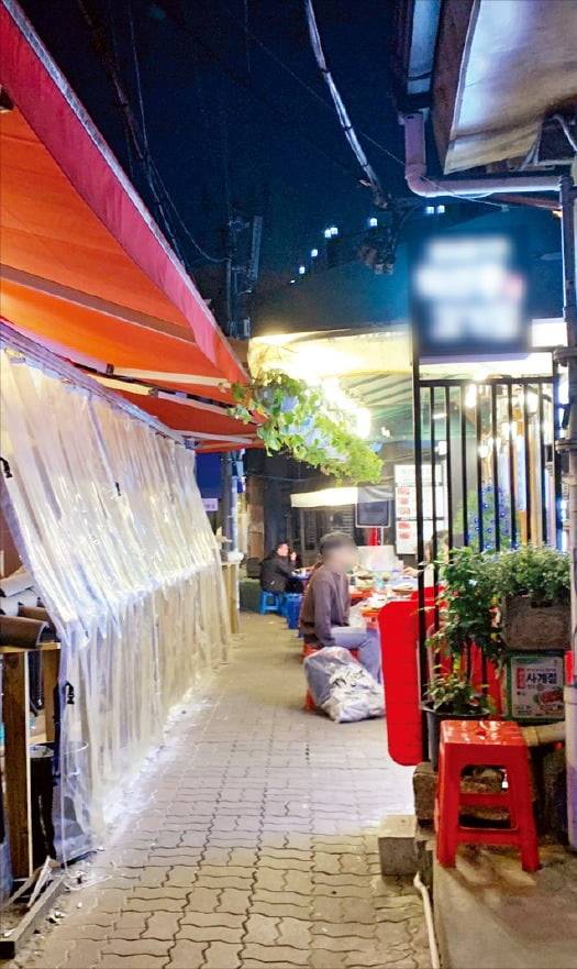 서울 종로구 익선동의 한 골목으로 오른쪽엔 불법 테라스와 테이블이, 왼쪽엔 짐을 쌓아 둔 캐노피 천막이 설치돼 통행을 방해하고 있다.   원종환  기자