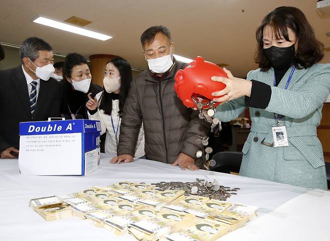 전주 노송동 주민센터 직원들이 얼굴없는 천사가 놓고 간 저금통을 개봉하고 있다.(전주시 제공)