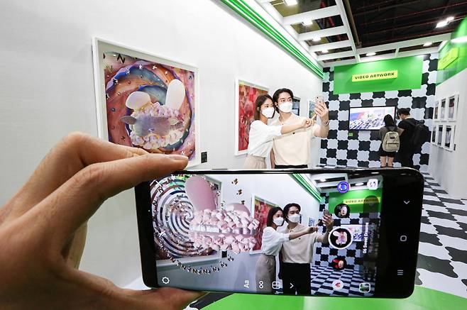 Visitors to Kiaf Plus check out the "Metabun_ny World" exhibition by using artificial reality technology on their smartphones. (Han Sung Motor)