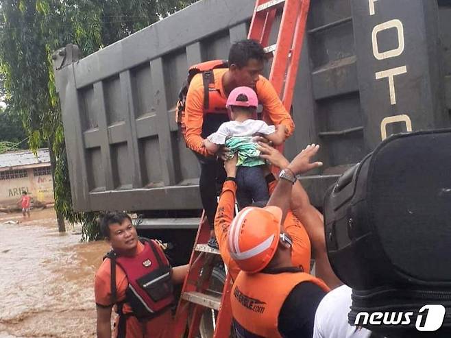 26일(현지시간) 홍수가 난 필리핀 프라리델에서 구조대원들이 한 아이를 구조해 안전한 곳으로 대피시키고 있다. 지난 크리스마스에 필리핀 남동부에 쏟아진 홍수로 30명 이상이 숨졌다. ⓒ 로이터=뉴스1 ⓒ News1 권진영 기자