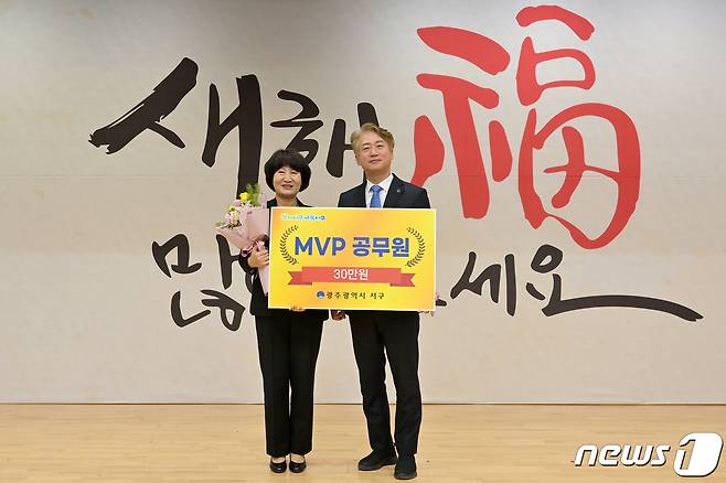 2일 열린 광주 서구 시무식에서 강미숙 세무2과 수납팀장(왼쪽)이 제1호 MVP 공무원으로 선정된 뒤 김이강 청장과 기념촬영하고 있다. (광주 서구 제공) 2023.1.2/뉴스1