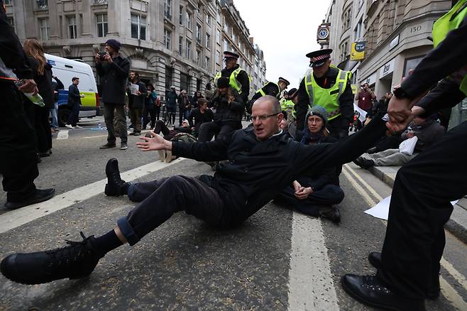 ‘멸종 반란(Extinction Rebellion·XR)’ 운동가들이 2021년 11월13일(현지시간) 영국 런던에서 런던 시장 취임을 기념해 열린 ‘로드 메이어 쇼’가 열리던 중 도로를 막아 런던 경찰에 끌려가고 있다. | 게티이미지