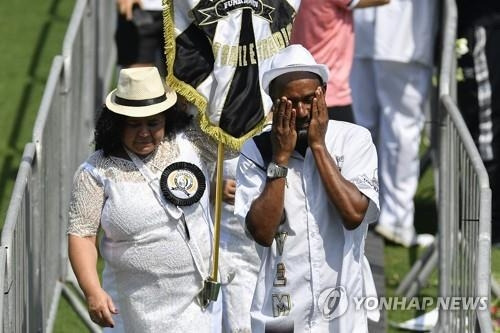 축구 팬이 조문 순서를 기다리던 중 흘러내리는 눈물을 닦으며 슬퍼하고 있다.  [산투스=AP/연합뉴스)