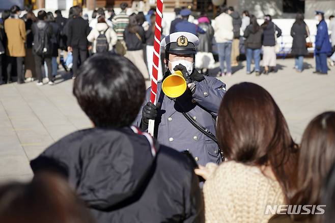 [도쿄=AP/뉴시스] 3일 일본 도쿄의 메이지 신궁에서 한 경찰관이 '하츠모데'를 위해 신사를 찾은 방문객들을 안내하고 있다. '하츠모데'는 새해에 처음으로 신사를 참배하는 행사로 사람들은 신에게 지난 1년 동안 돌봐주신 것에 감사하고 새해의 평안을 빈다. 2023.01.03.