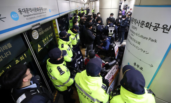 3일 오전 서울 지하철 4호선 동대문역사문화공원역 승강장에서 전국장애인차별철폐연대(전장연) 회원들이 254일차 장애인 권리예산 입법 쟁취 지하철 선전전을 위해 탑승하려던 중 저지하는 서울지하철공사 직원 및 경찰들에게 가로막혀 있다. 전장연은 이날 4호선 성신여대입구 역에서 탑승했다가 동대문역사문화공원 역에서 하차했다. 다시 탑승하고 삼각지역으로 향해 집회를 이어가려고 했으나 교통공사와 경찰의 탑승 저지로 이동하지 못하고 있다. 2023.01.03 뉴시스